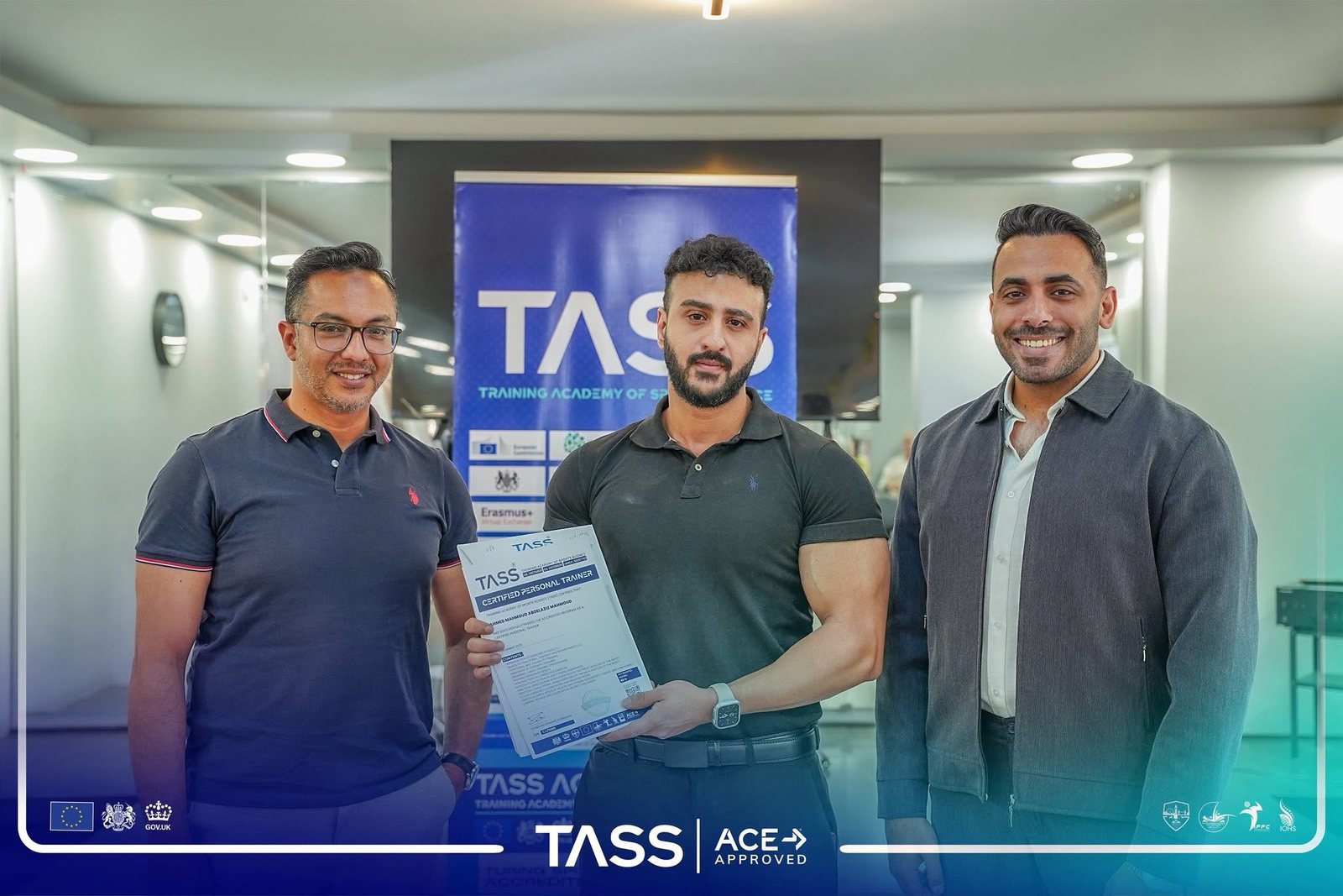 Dagher Mahmoud holding his TASS Certified Personal Trainer certificate, with two TASS Academy representatives either side of him.
